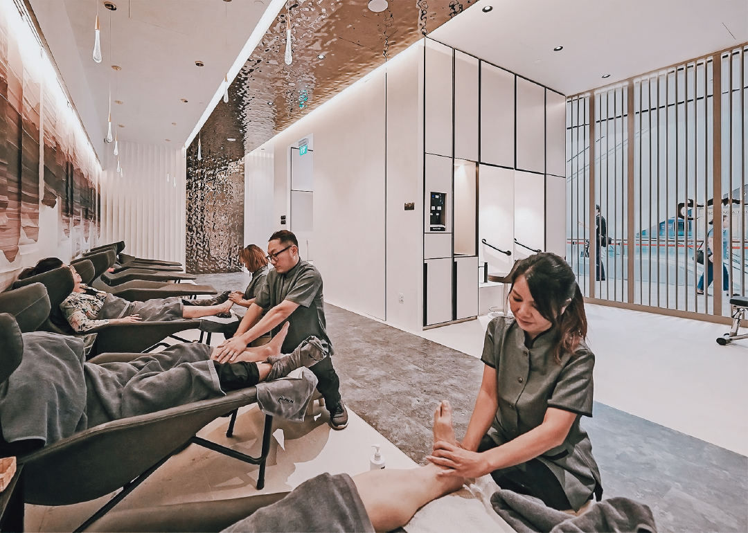 masseuses giving customers a foot rub at ning foot & back spa at jewel changi airport, singapore