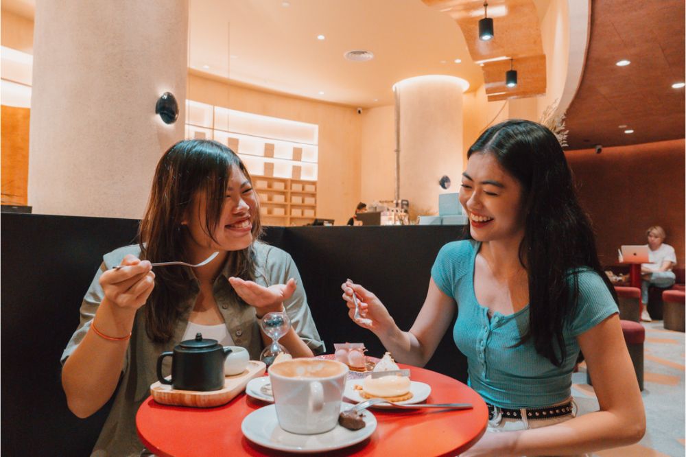 a pair of friends having a cup of tea and some cakes at nesuto jewel, coffee shop in changi airport singapore