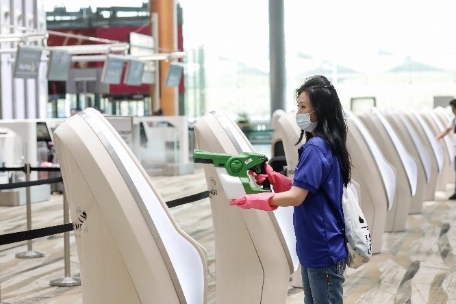 A woman using the antimicrobial spray at a self-check-in counter
