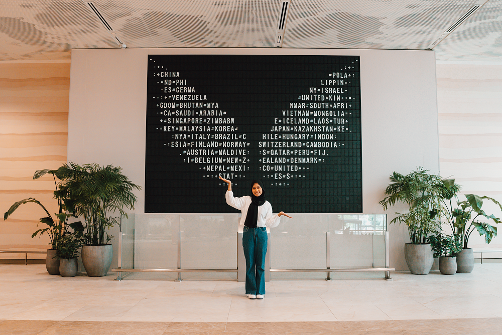 Visitor posing in front of the new interactive exhibit made from a repurposed flight information display board.