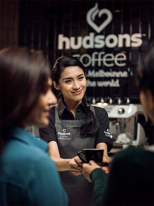 A barista serving coffee at Hudson’s Coffee station.