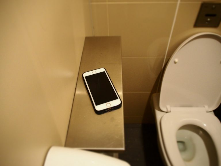 Mobile phone placed on shelf of Changi toilet cubicles.