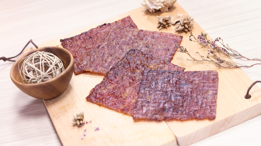 Picture of Bak Kwa served on top of pieces of wood and decorated with flowers