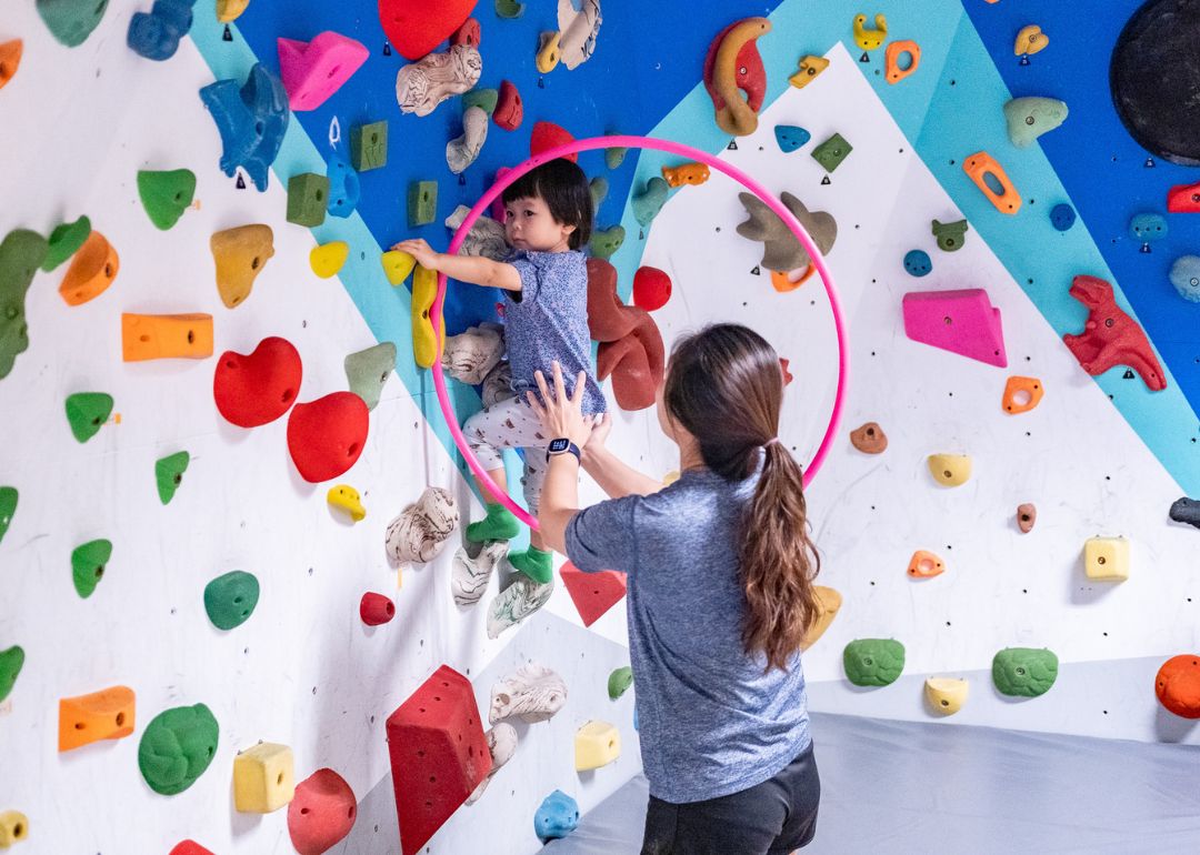 a young child climbing bouldering wall with help of instructor at changi airport t3 during a private party