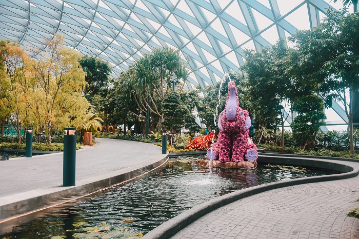 Wide view of Topiary Walk with pink elephant topiary projecting water into pond