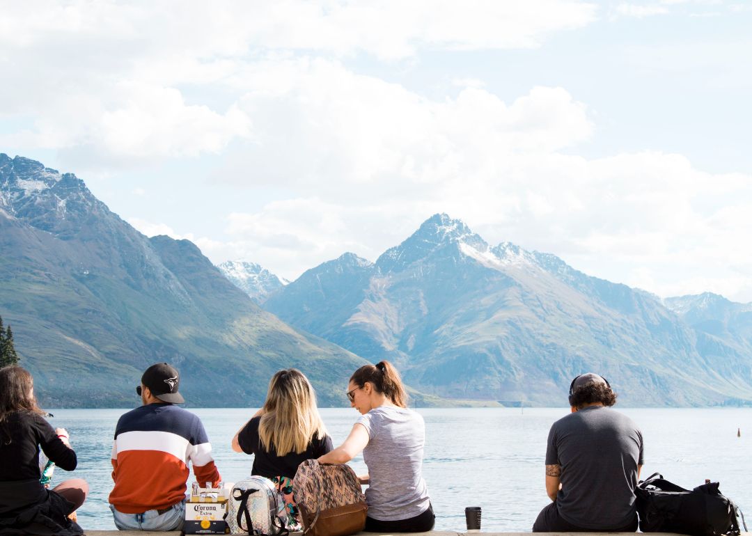 travellers from different countries sit by a lake comparing the best travel insurance companies