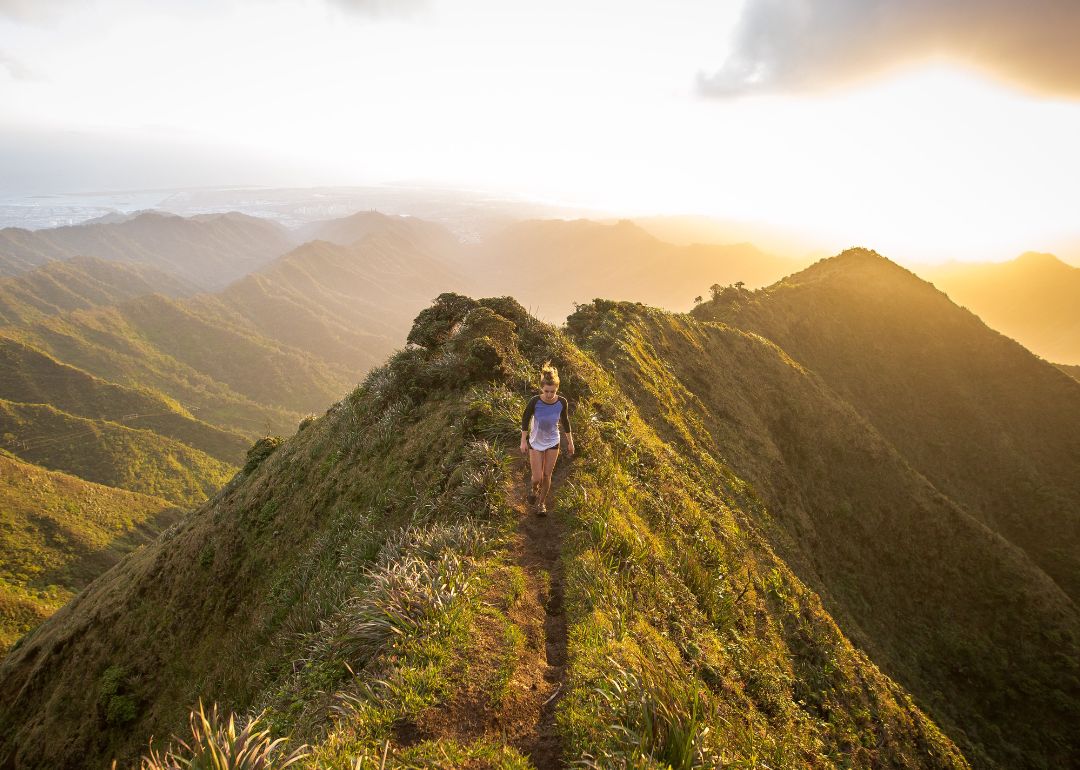woman bravely walks atop atop haiku stairs in hawaii covered by travel insurance