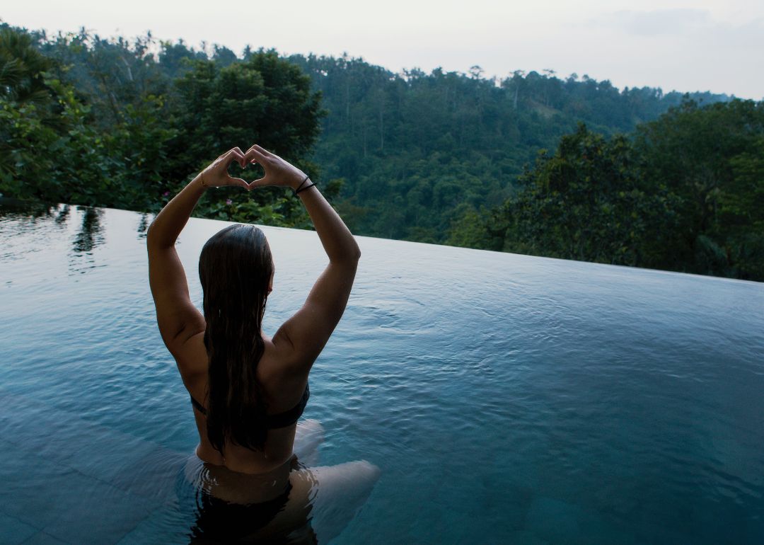 woman poses for photo in infinity pool after purchasing travel insurance for short getaway