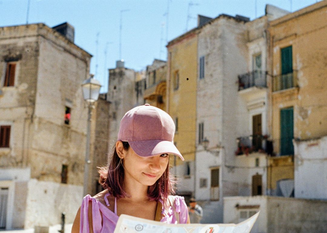 woman wearing cap looks happy she bought travel insurance for her holiday