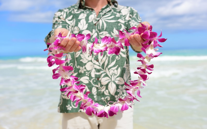 Man in tropical shirt holding lei