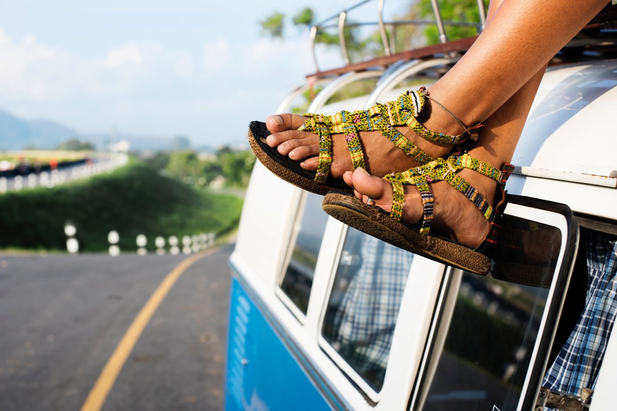 A relaxed pair of feet, dangling from the top of a travel bus