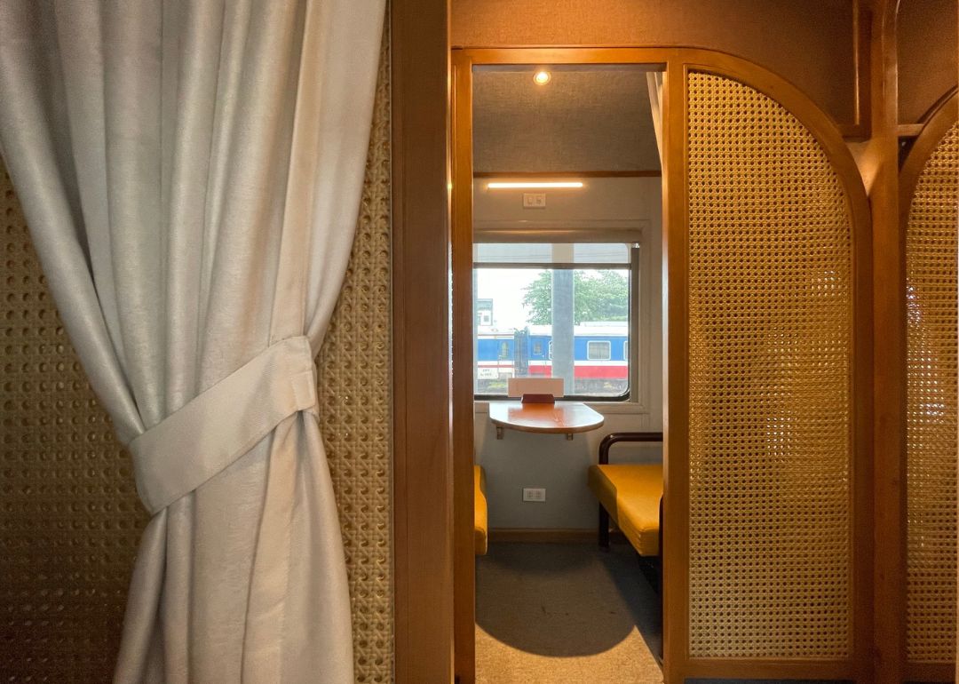 Interior of The Vietage train showing a private booth and a view of the station outside the window.