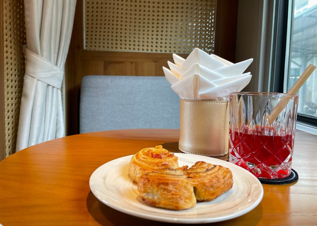 A plate of pastries with a beverage sits on the table by the seats.