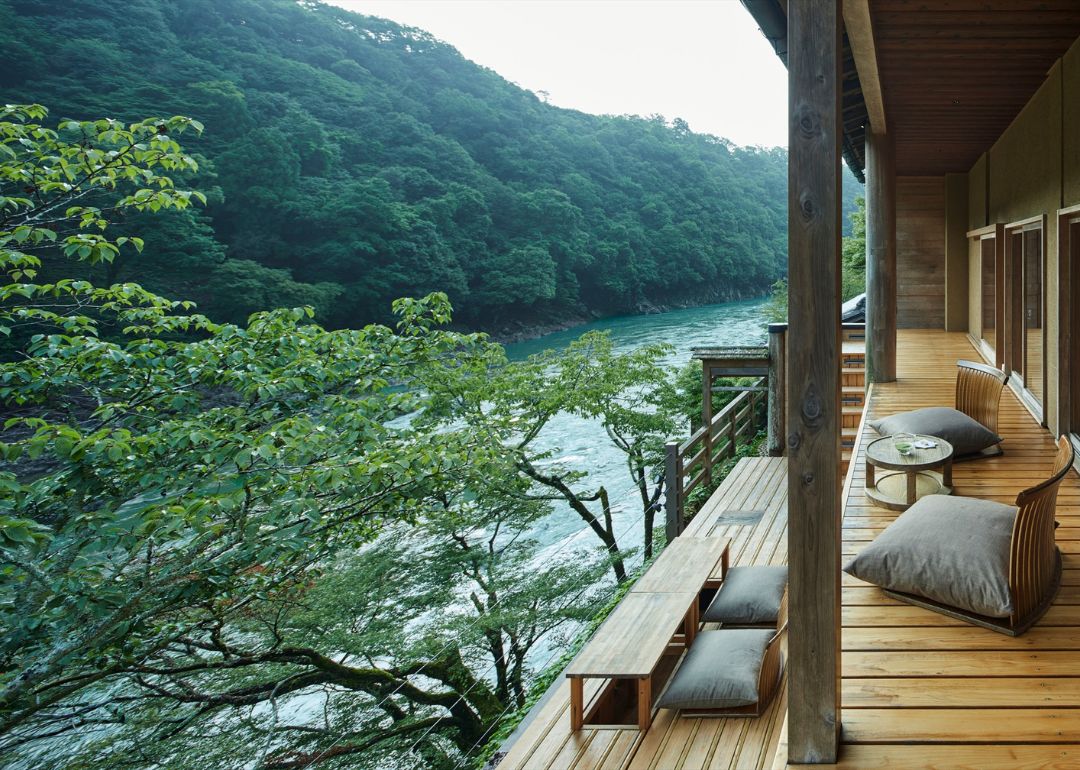 forested view of kyoto river from room balcony at hoshinoya ryokan