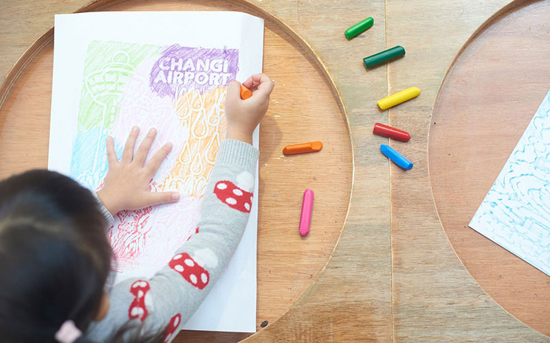 A kid colouring an artwork with crayon