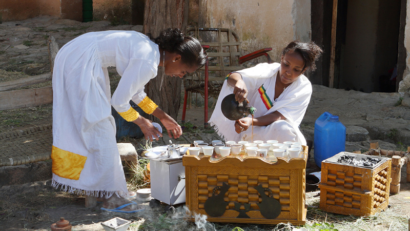 Women in traditional Ethiopian outfits prepare for the Coffee Ceremony
