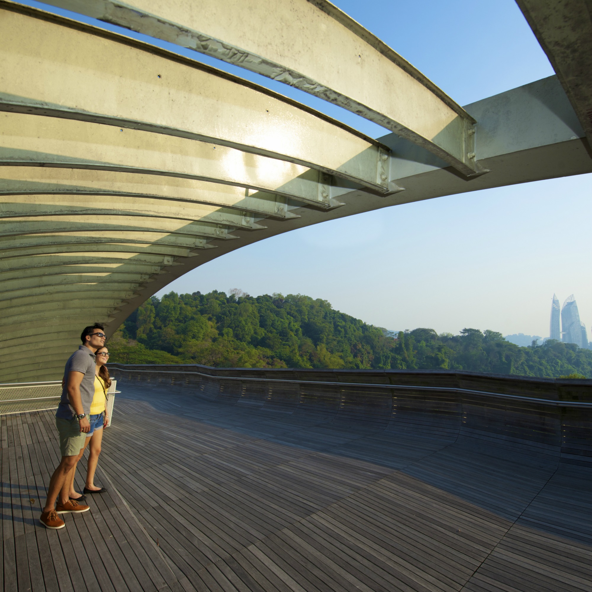 A couple standing on the Henderson Waves bridge with the Singapore skyline in the background