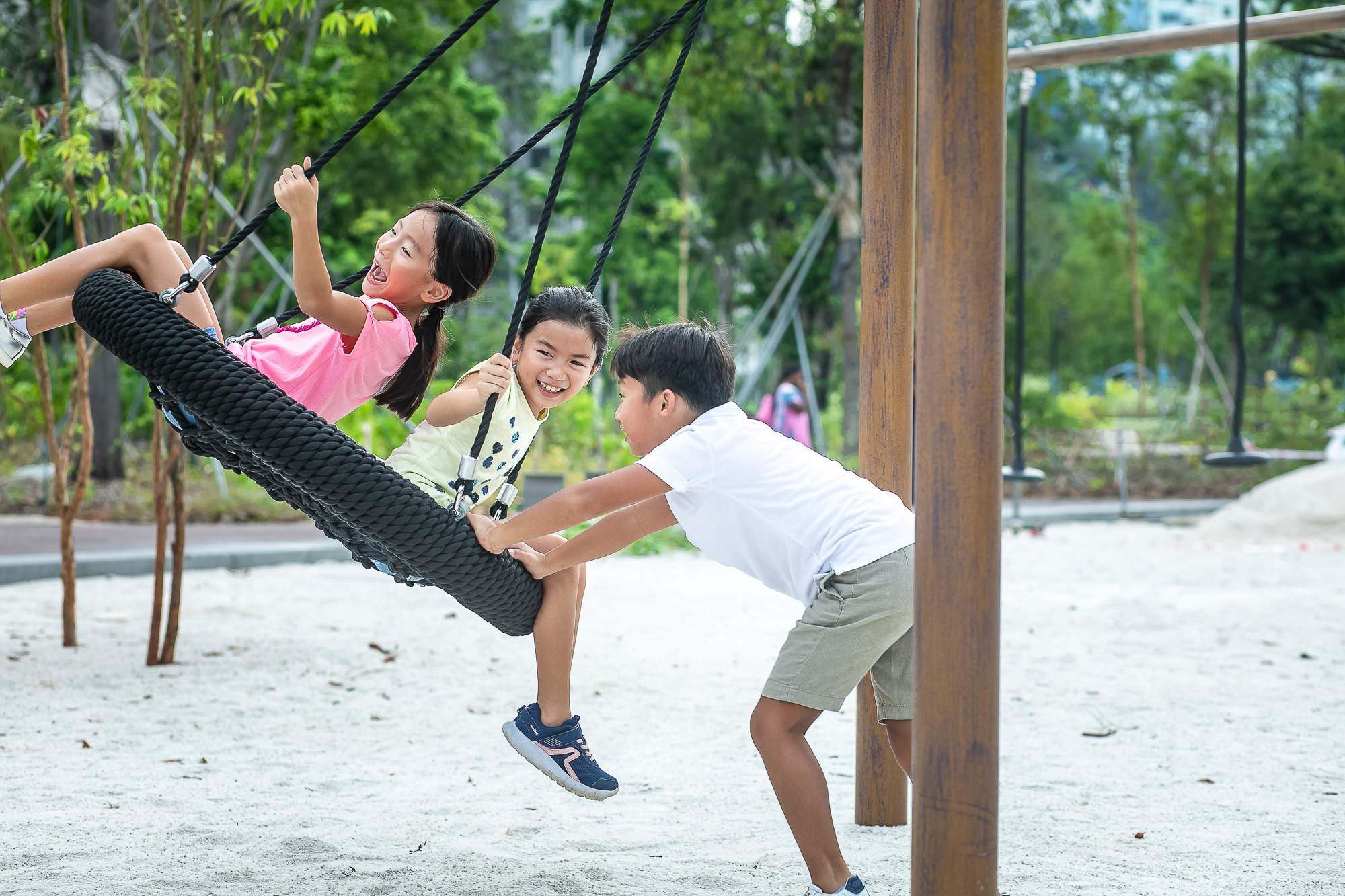 three kids playing at a forest ramble playground at jurong lake gardens, west area of singapore