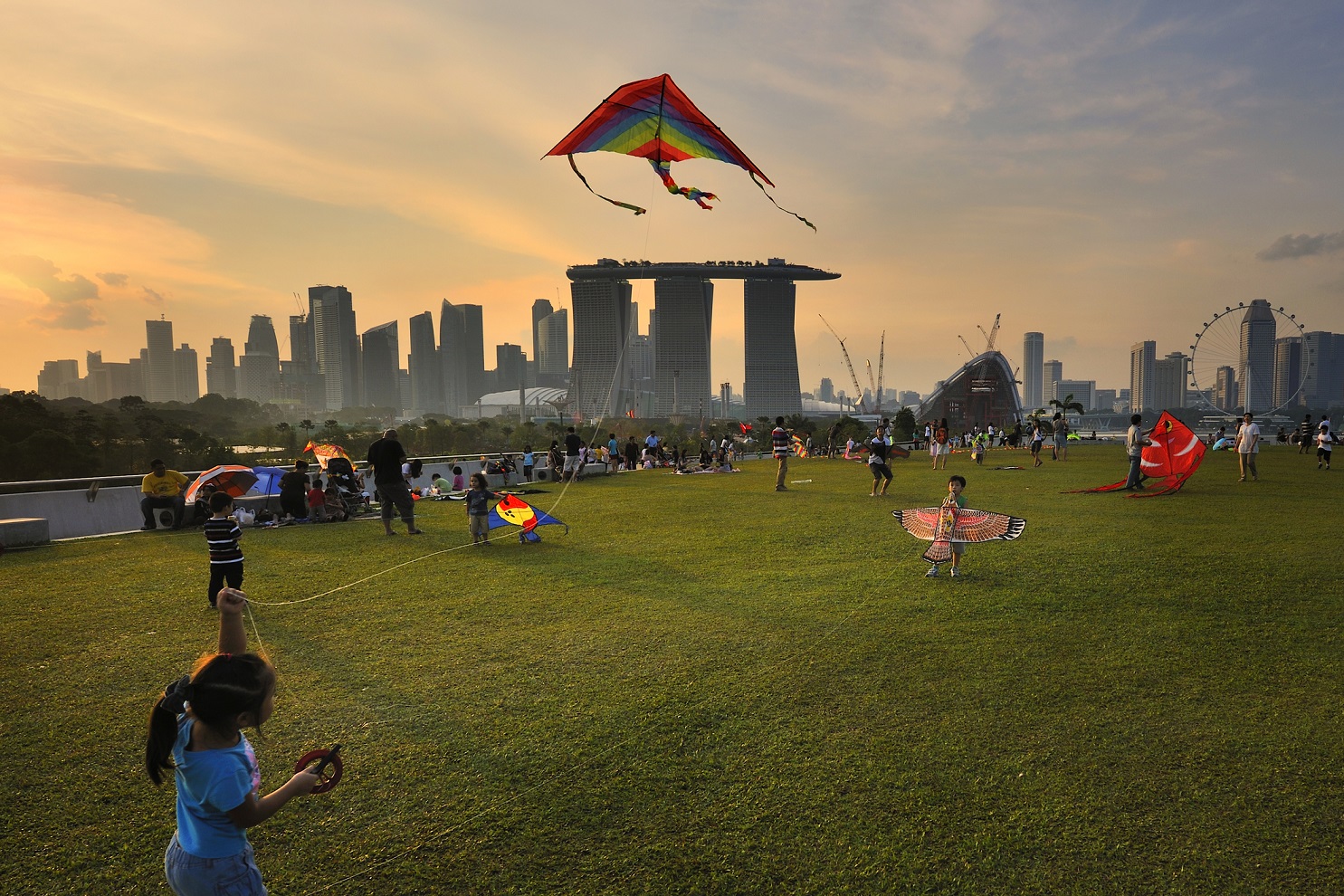 Children with their families flying kites at Marina Barrage with the Singapore skyline in the background