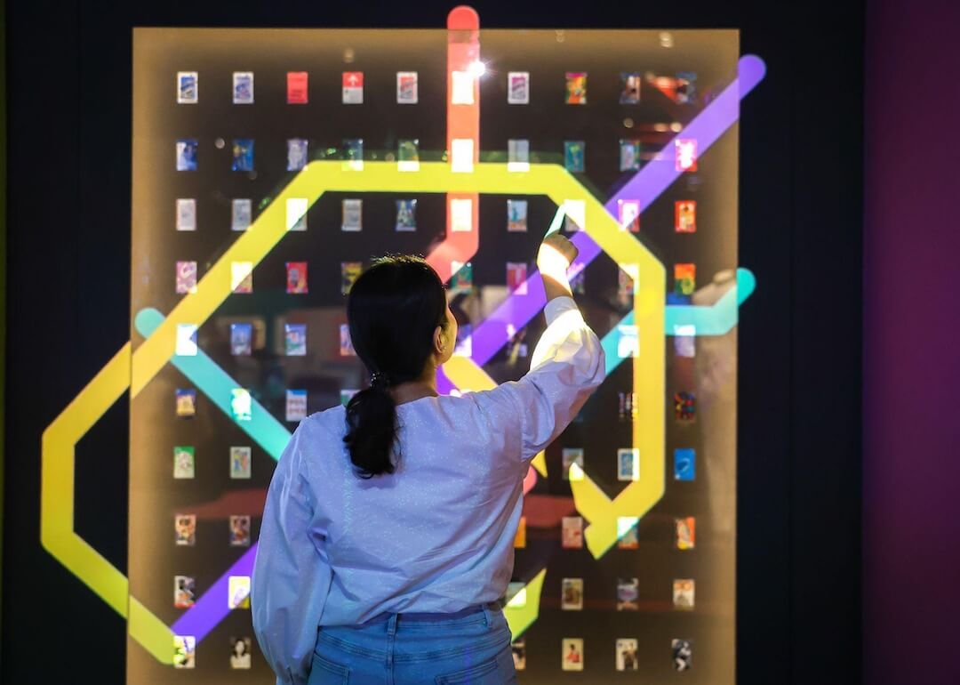 a lady interacts with a light projection featuring the mrt route map, with transitlink cards displayed in the background