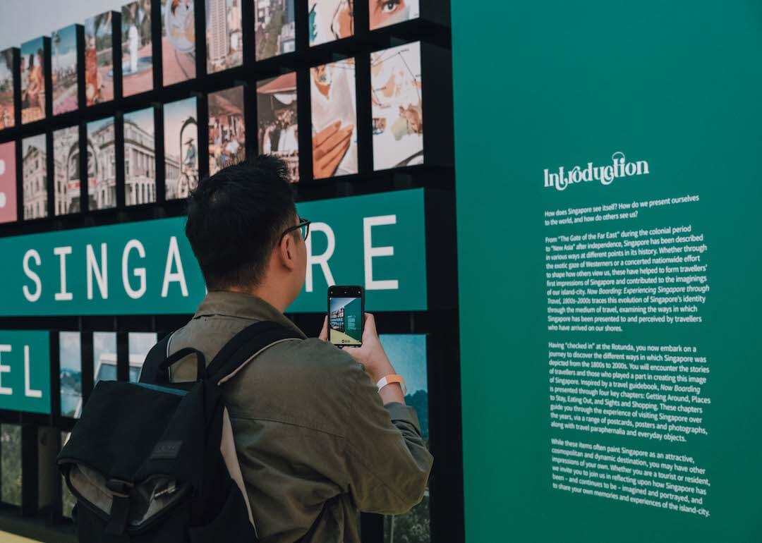 visitor reading the introduction panel at the now boarding exhibition entrance of the national museum of singapore