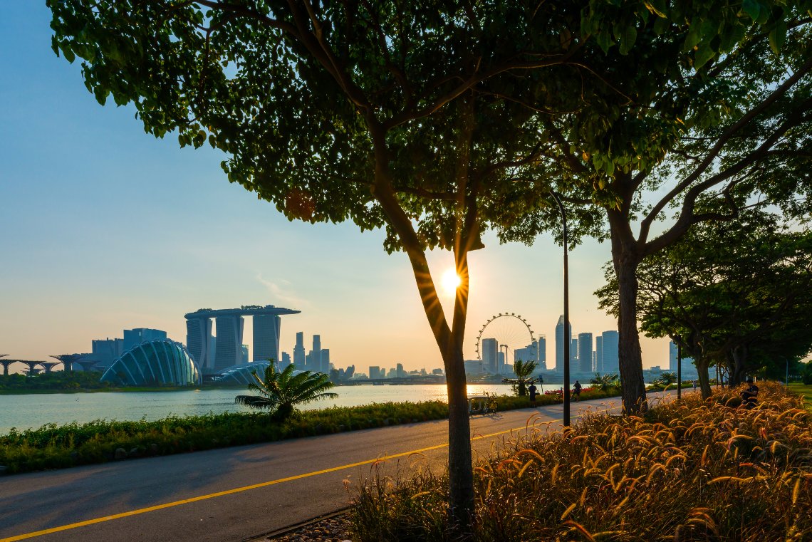 east coast park cycling trail towards downtown singapore with sun setting behind
