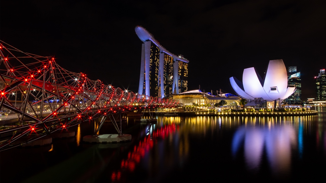 helix bridge, marina bay sands and artscience museum against singapore skyline at night